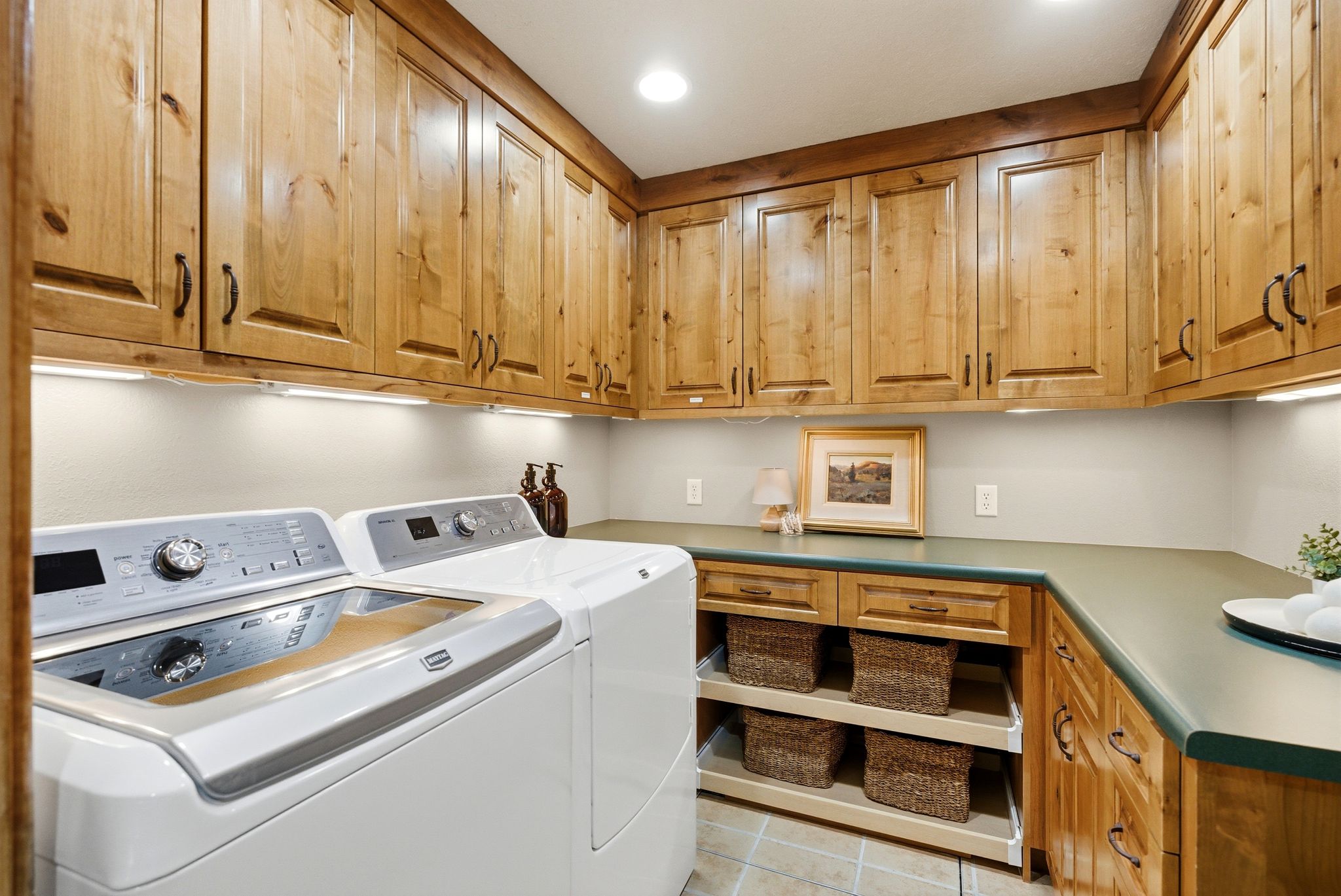 Laundry room featuring extensive wood cabinetry, under-cabinet lighting, and a durable countertop