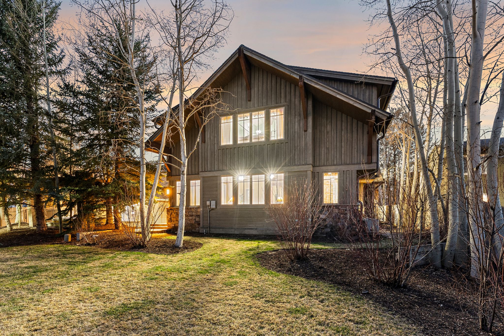 Exterior featuring vertical wood siding, stone accents, and multiple window arrays