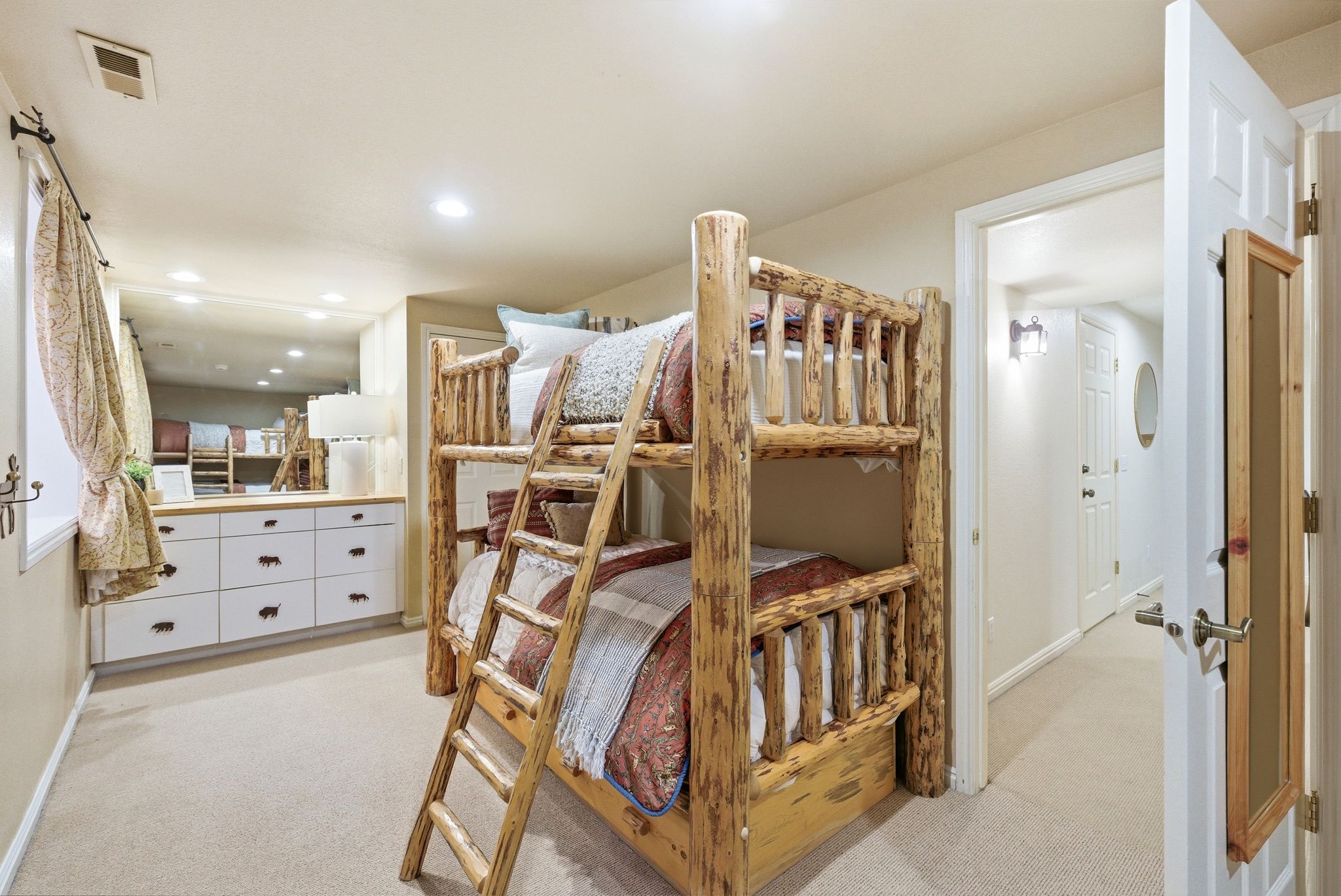 Carpeted room featuring a rustic wood-finish bunk bed, built-in white dresser cabinetry with dark hardware, recessed lighting, and a white paneled door