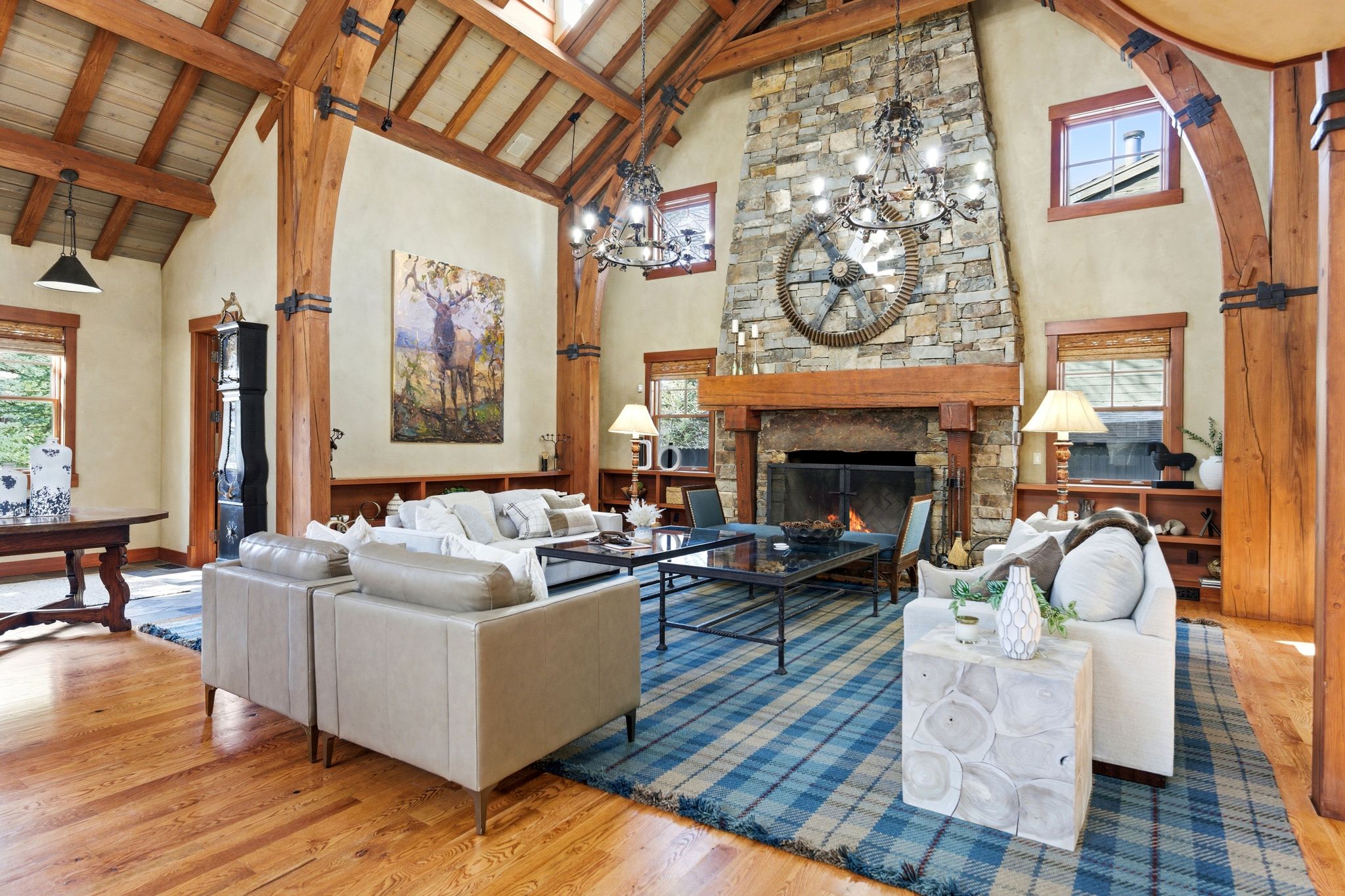 Great room featuring a prominent stone fireplace with a substantial wood mantel, exposed wood beam ceiling, and skylights