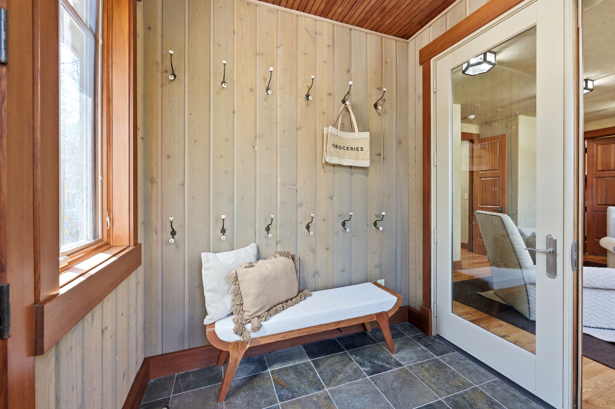 Entryway featuring vertical wood paneling and a natural wood trim window