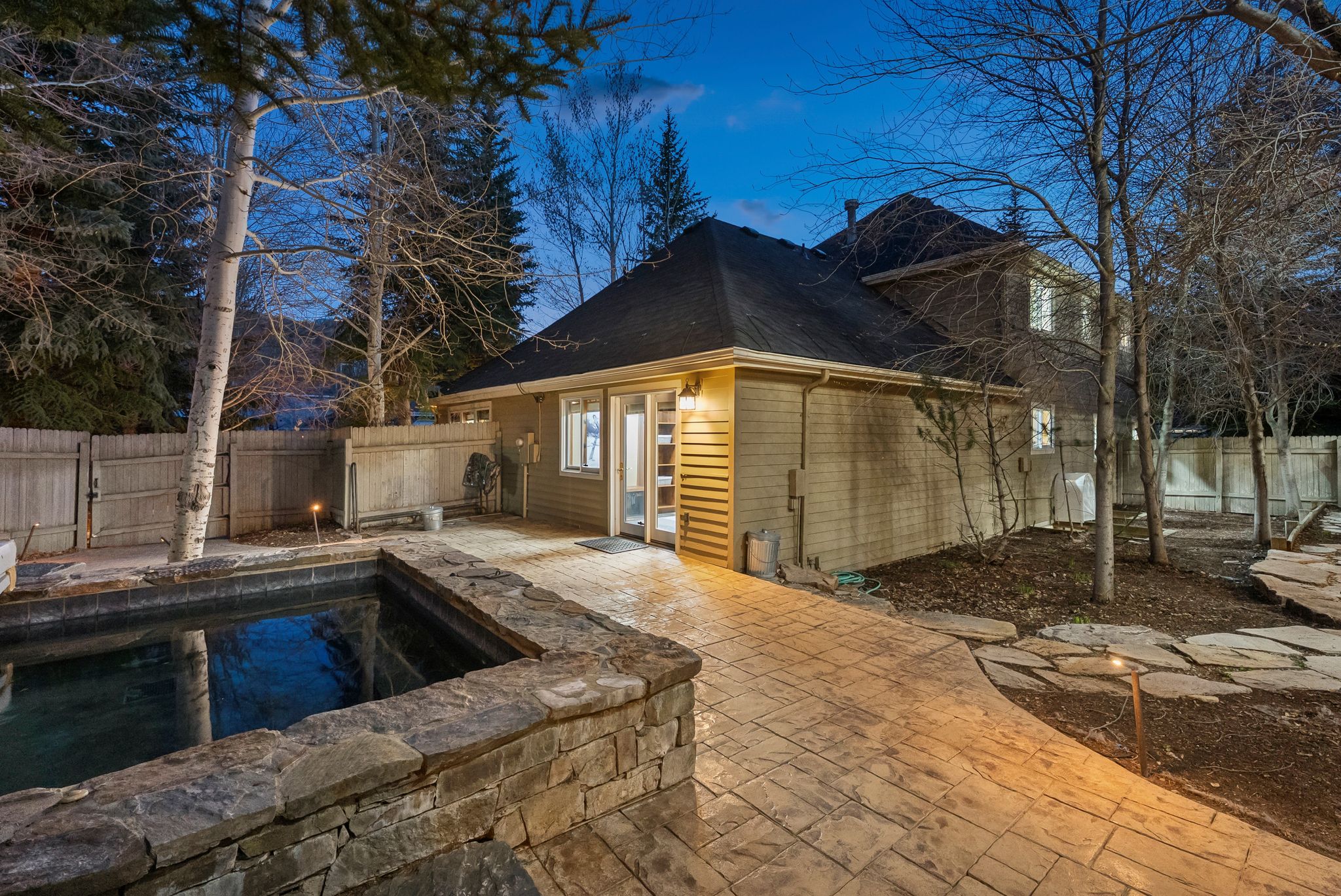 Exterior featuring a private spa with stone surround, stamped concrete patio, and flagstone pathway
