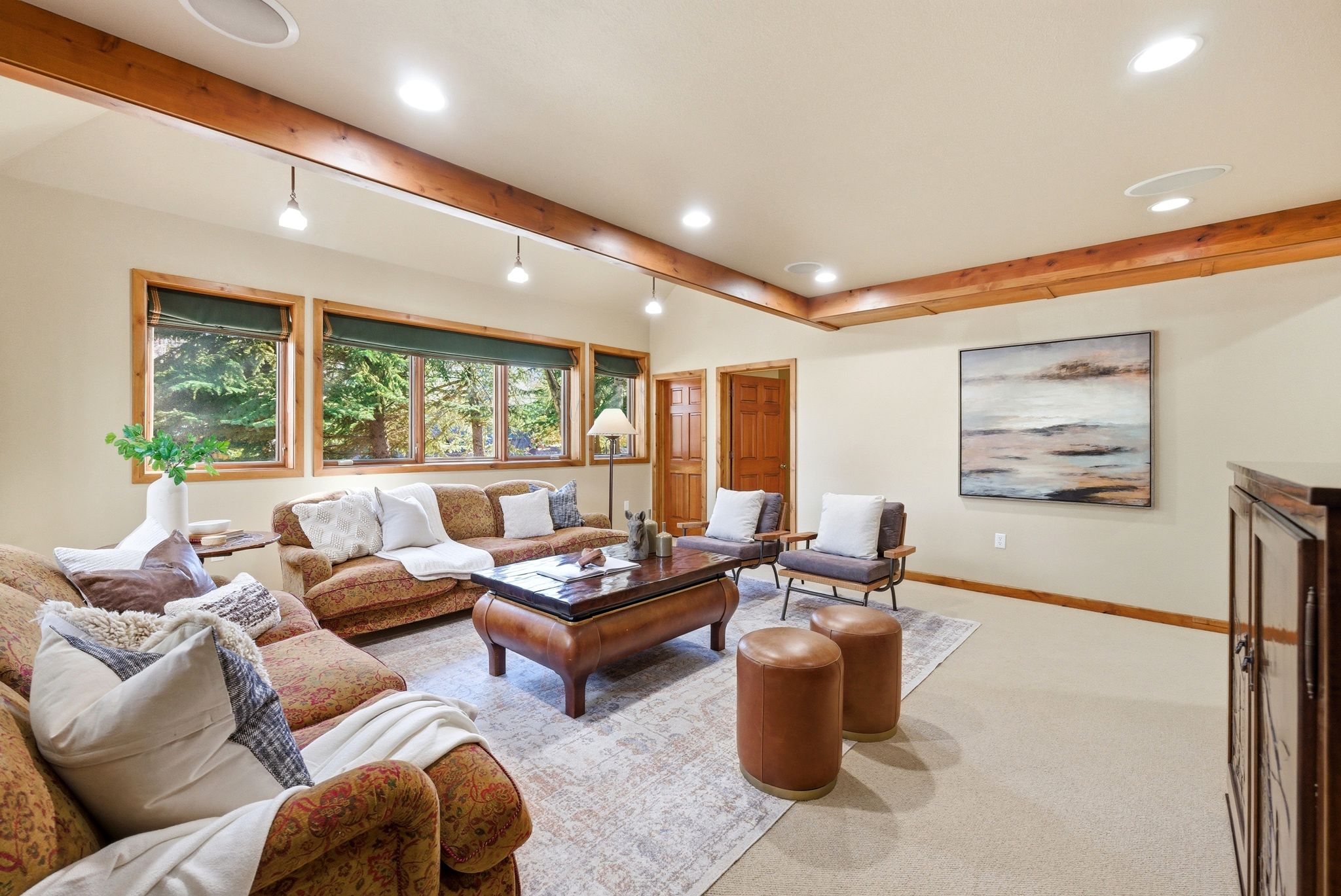 Living area featuring exposed wood beams, recessed lighting, and multiple windows with wood trim