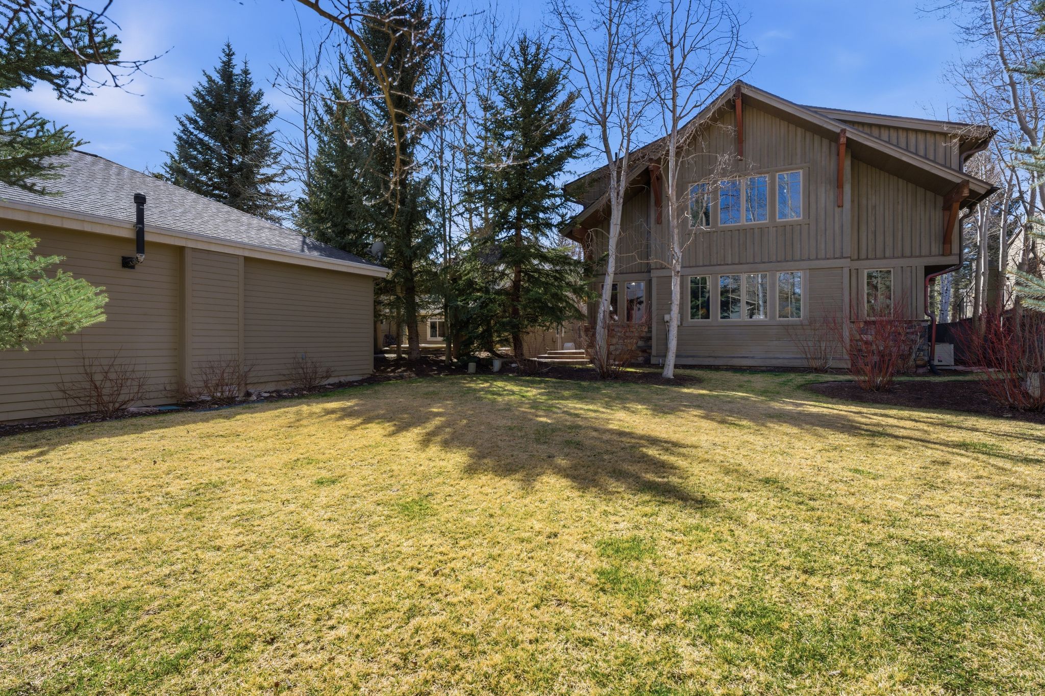 Expansive lawn with mature trees and two distinct structures