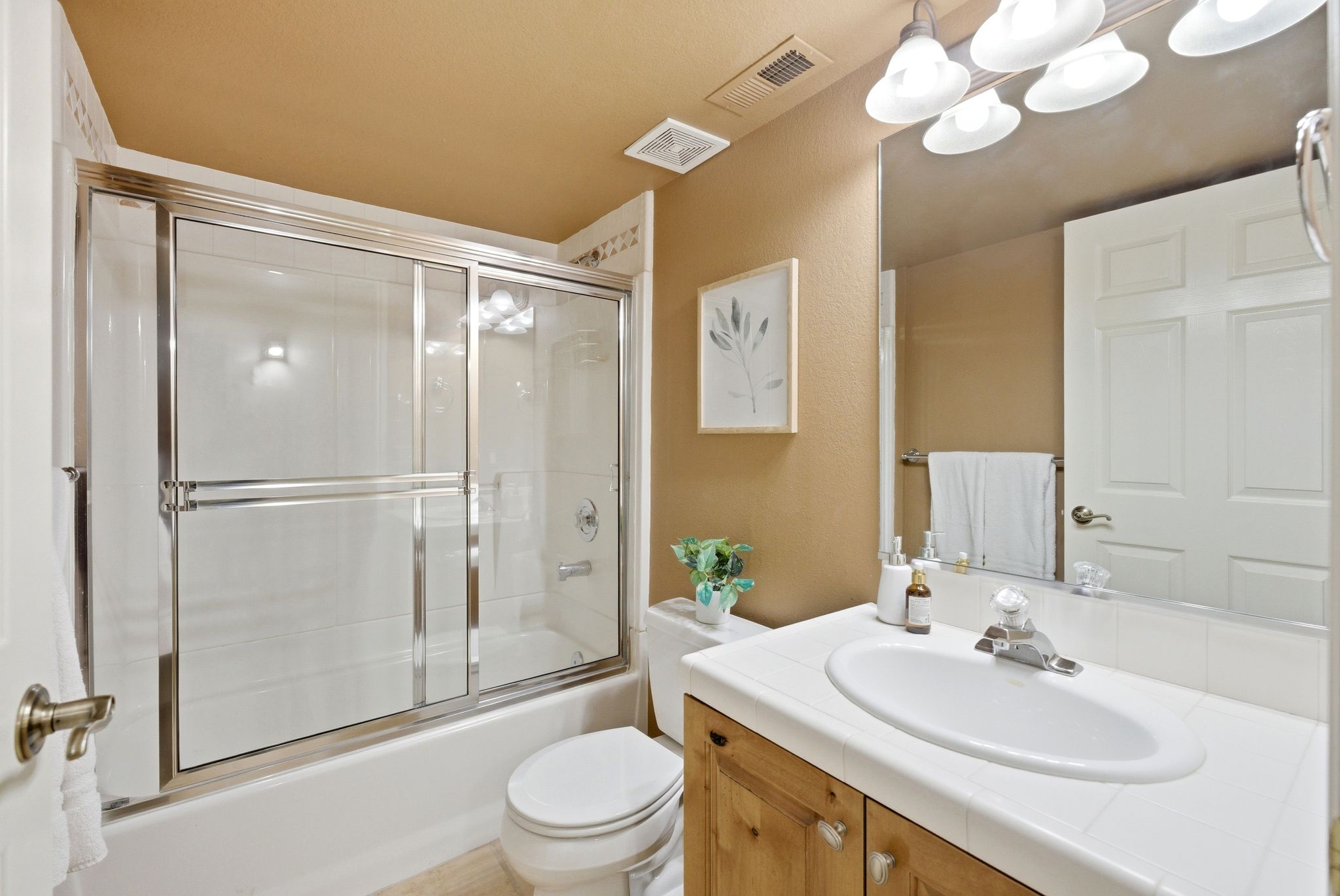 Full bathroom featuring a white tub and shower combination with a sliding glass enclosure