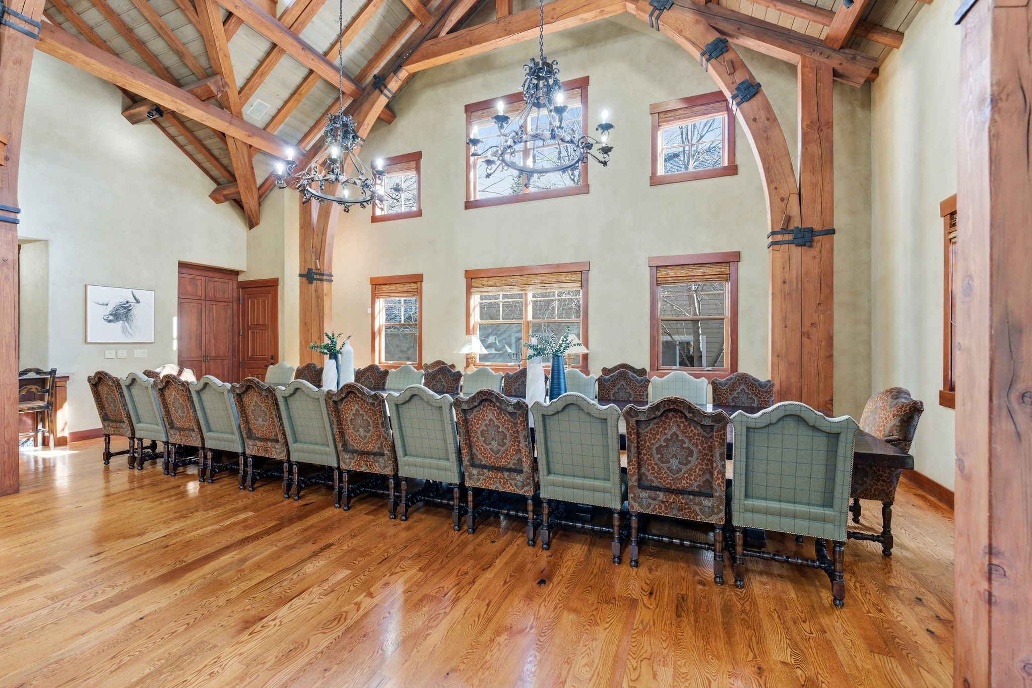Grand dining area featuring a vaulted wood-beamed ceiling, hardwood flooring, and multiple windows with wood trim