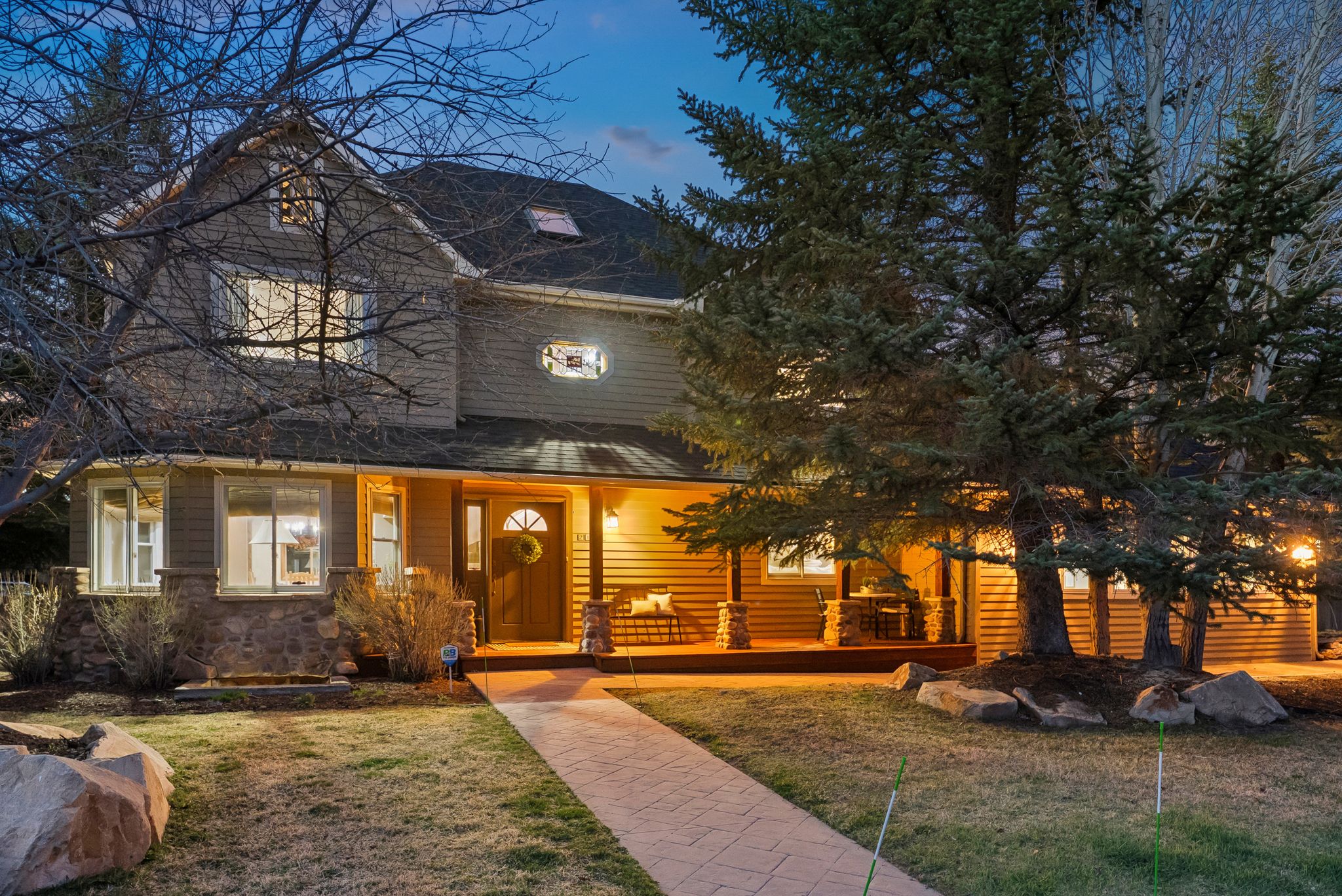 Two-story residence featuring a covered front porch, stone accents, horizontal siding, and multiple windows