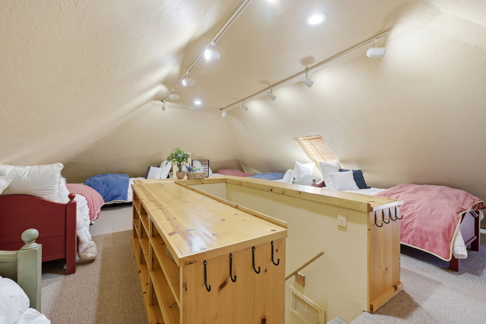 Spacious attic room with sloped ceilings, recessed lighting, and track lighting fixtures