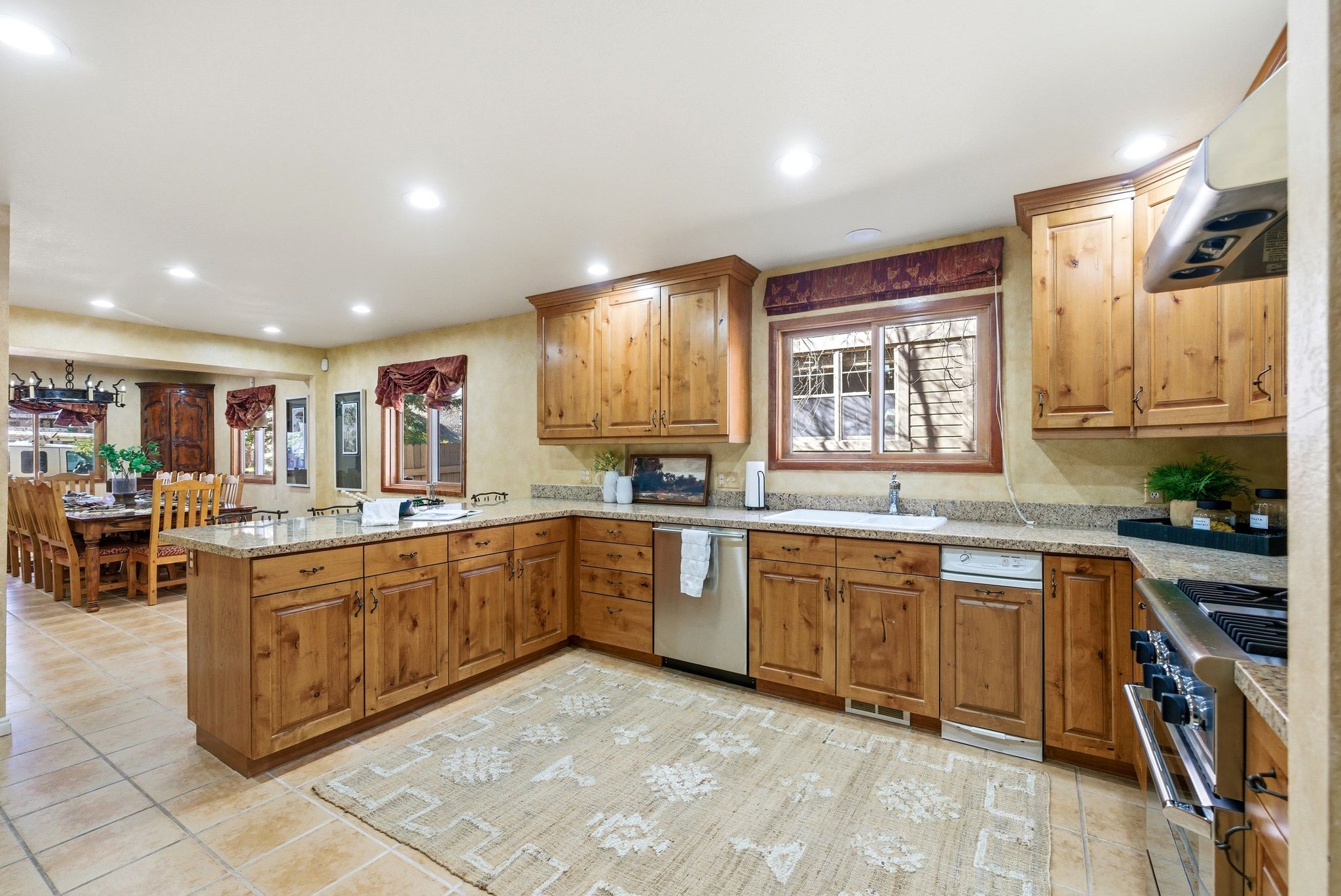 Kitchen featuring wood cabinetry, granite countertops, tile flooring, stainless steel appliances, and recessed lighting