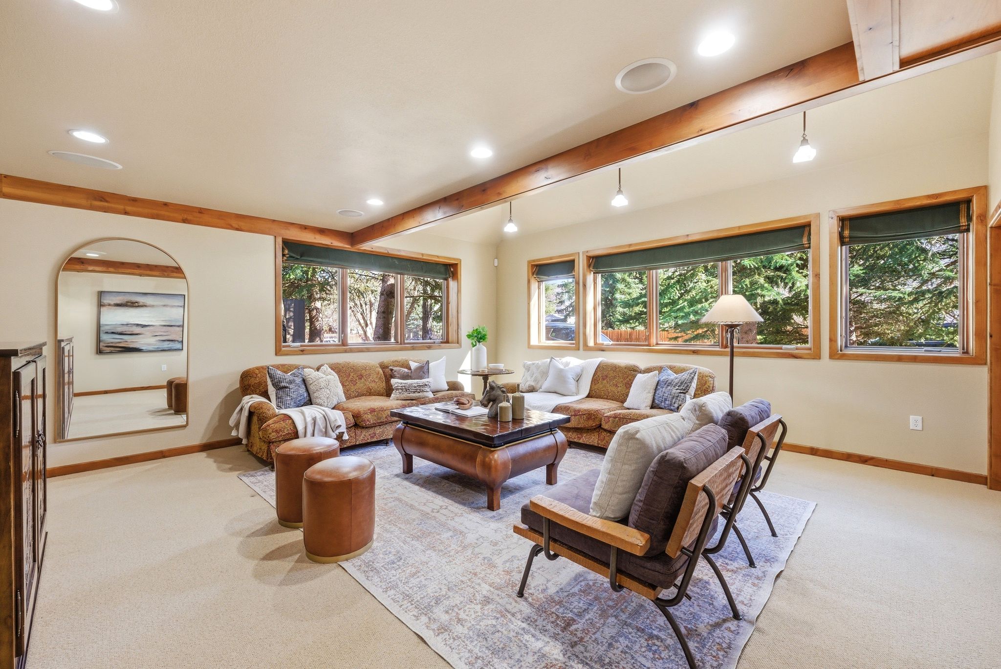Spacious living area featuring exposed wood beams, recessed lighting, and large windows with wood trim