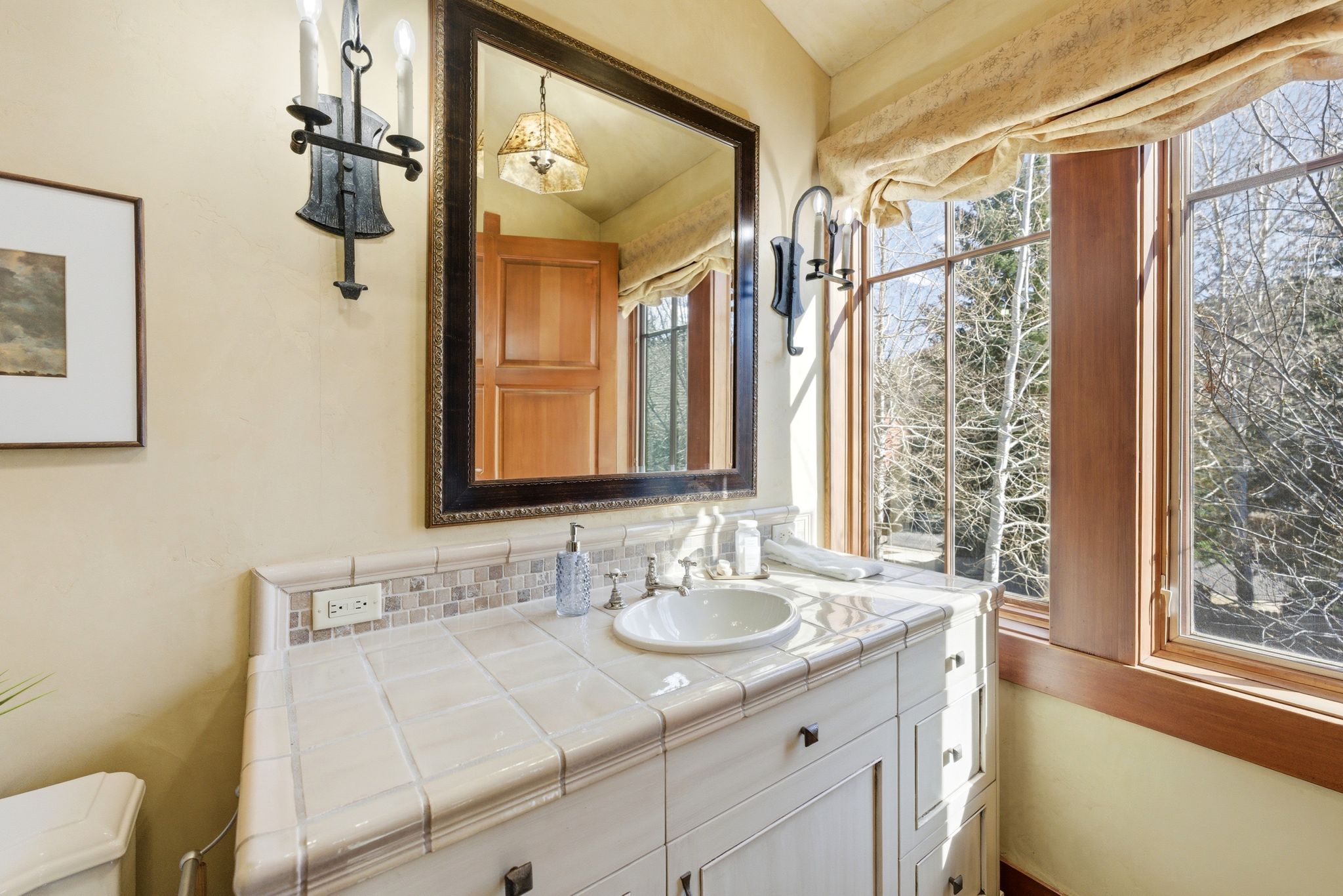 Bathroom vanity featuring a tiled countertop, undermount sink, and traditional fixtures