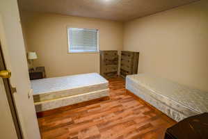 Interior room featuring wood-finish flooring, neutral wall paint, and a window with horizontal blinds