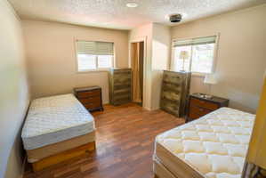Room featuring wood-finish flooring, two windows with blinds, and a built-in recessed ceiling light fixture