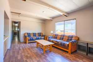Spacious living area featuring wood-finish flooring, a large sliding window, and a hallway entry
