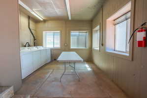 Dedicated laundry area featuring multiple appliances, durable concrete flooring, and vertical paneling
