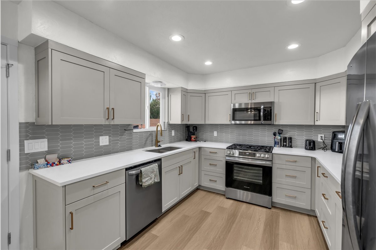 Modern kitchen featuring light gray cabinetry, white countertops, and a gray geometric tile backsplash