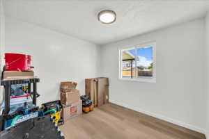 Bright interior room with white painted walls, wood-finish flooring, and a single window