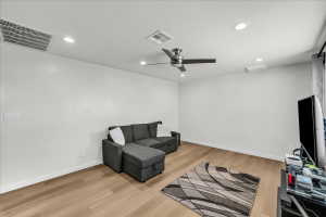 Spacious room with wood-finish flooring, recessed lighting, a ceiling fan with brushed nickel accents, and white baseboards