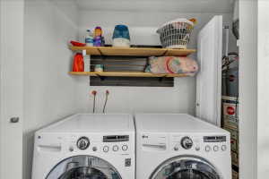 Dedicated laundry area featuring a front-loading washer and dryer, wall-mounted wooden shelving, and a water heater enclosure