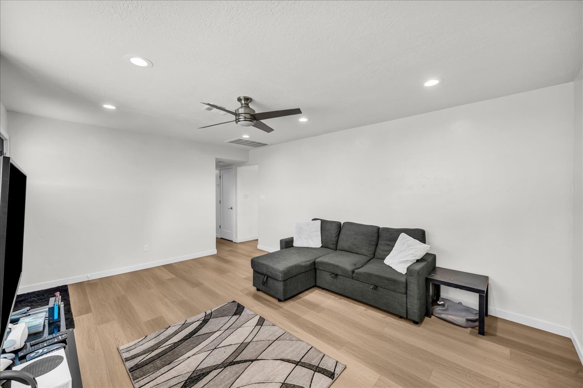 Open-concept living space featuring wood-finish flooring, recessed lighting, and a ceiling fan
