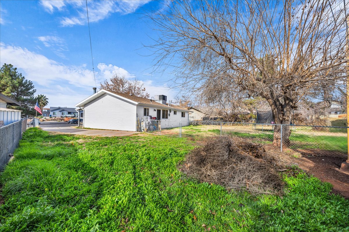 Expansive grass lawn with mature trees and perimeter chain-link fencing