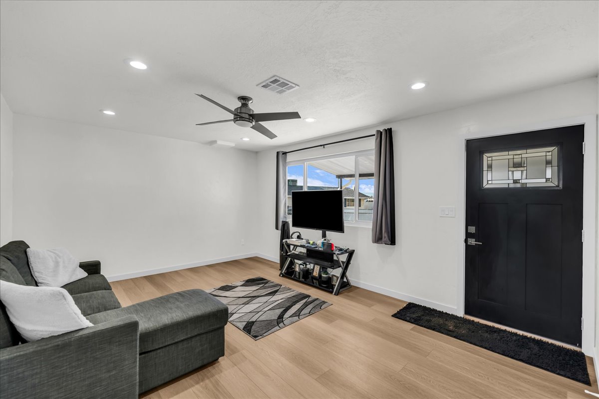 Spacious living area featuring wood-finish flooring, recessed lighting, and a modern ceiling fan