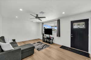 Spacious living area featuring wood-finish flooring, recessed lighting, and a modern ceiling fan