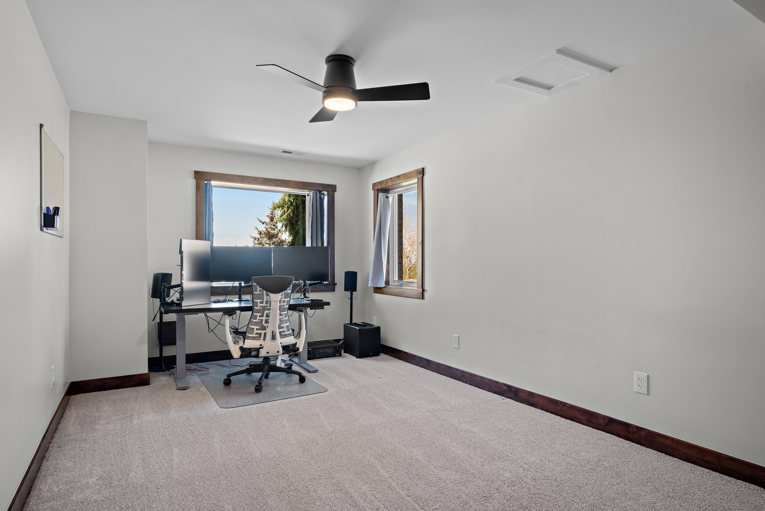 Carpeted room with a ceiling fan light fixture and a window featuring wood trim
