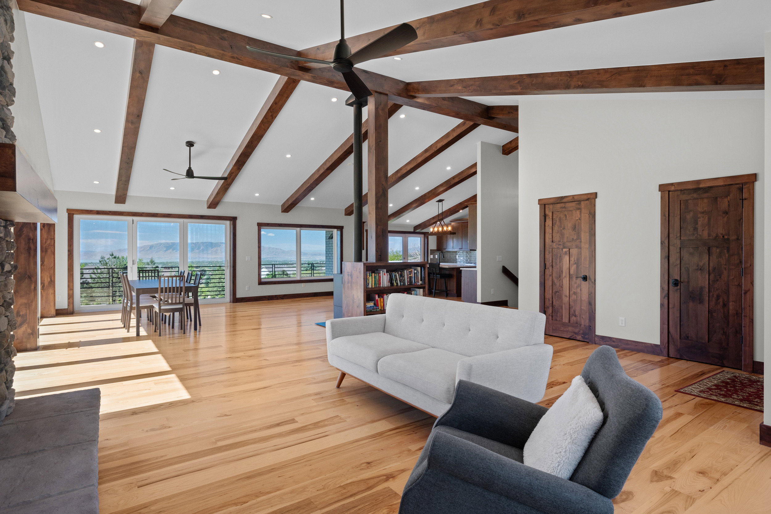 Open-concept living area featuring exposed wood beams, vaulted ceilings, recessed lighting, and light wood-finish flooring