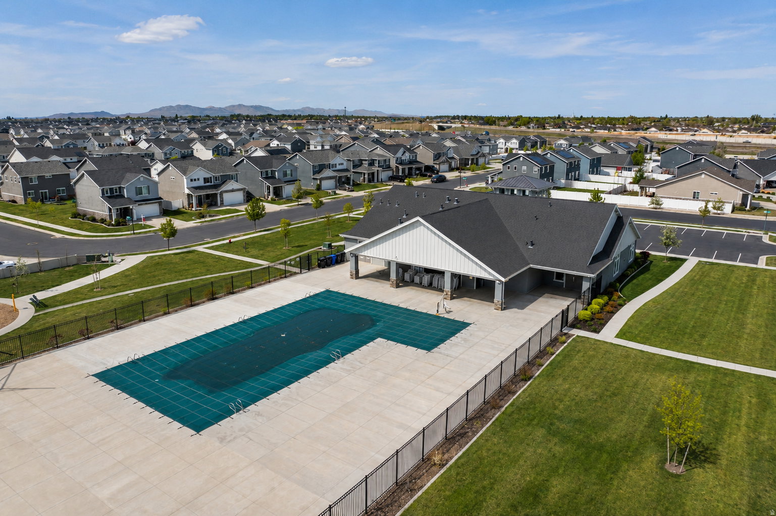 Community recreational building featuring a covered swimming pool, paved patio, and adjacent green space