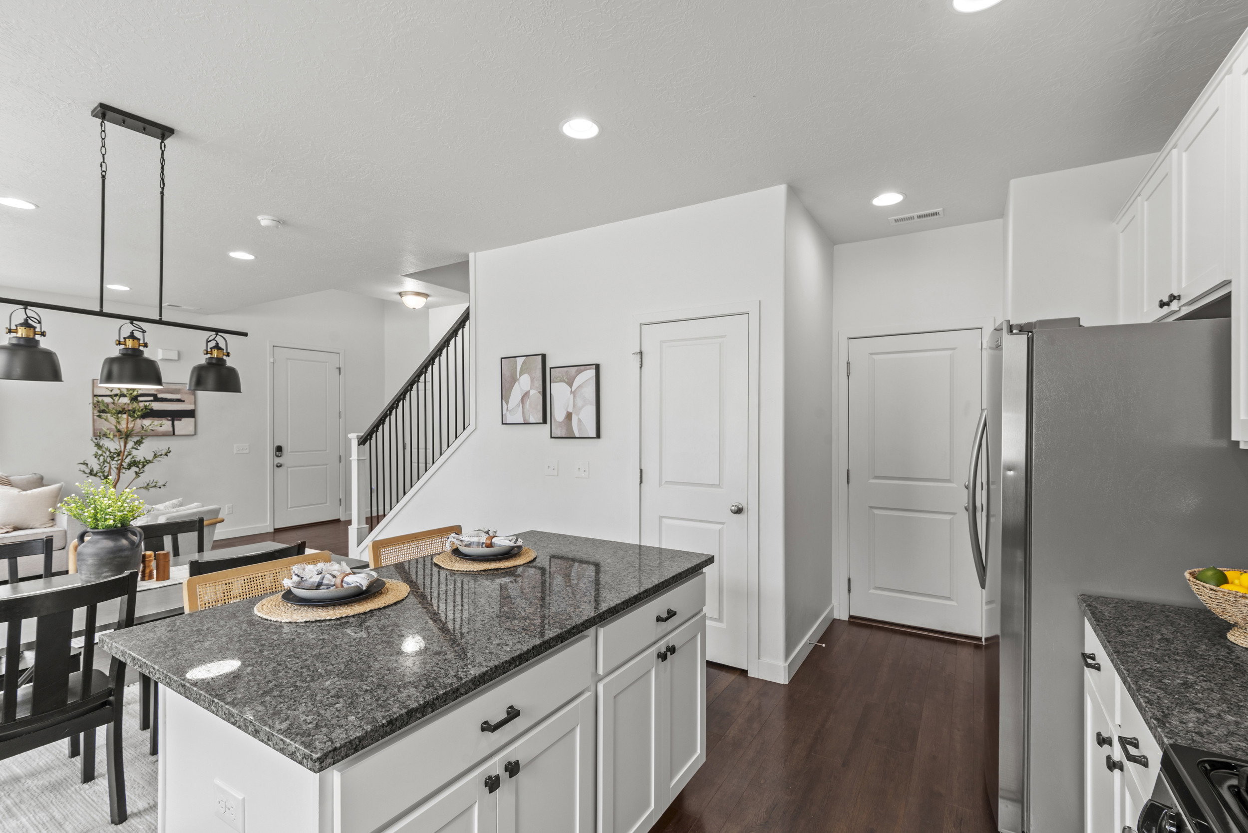 Kitchen island featuring a dark granite countertop and white cabinetry with black hardware