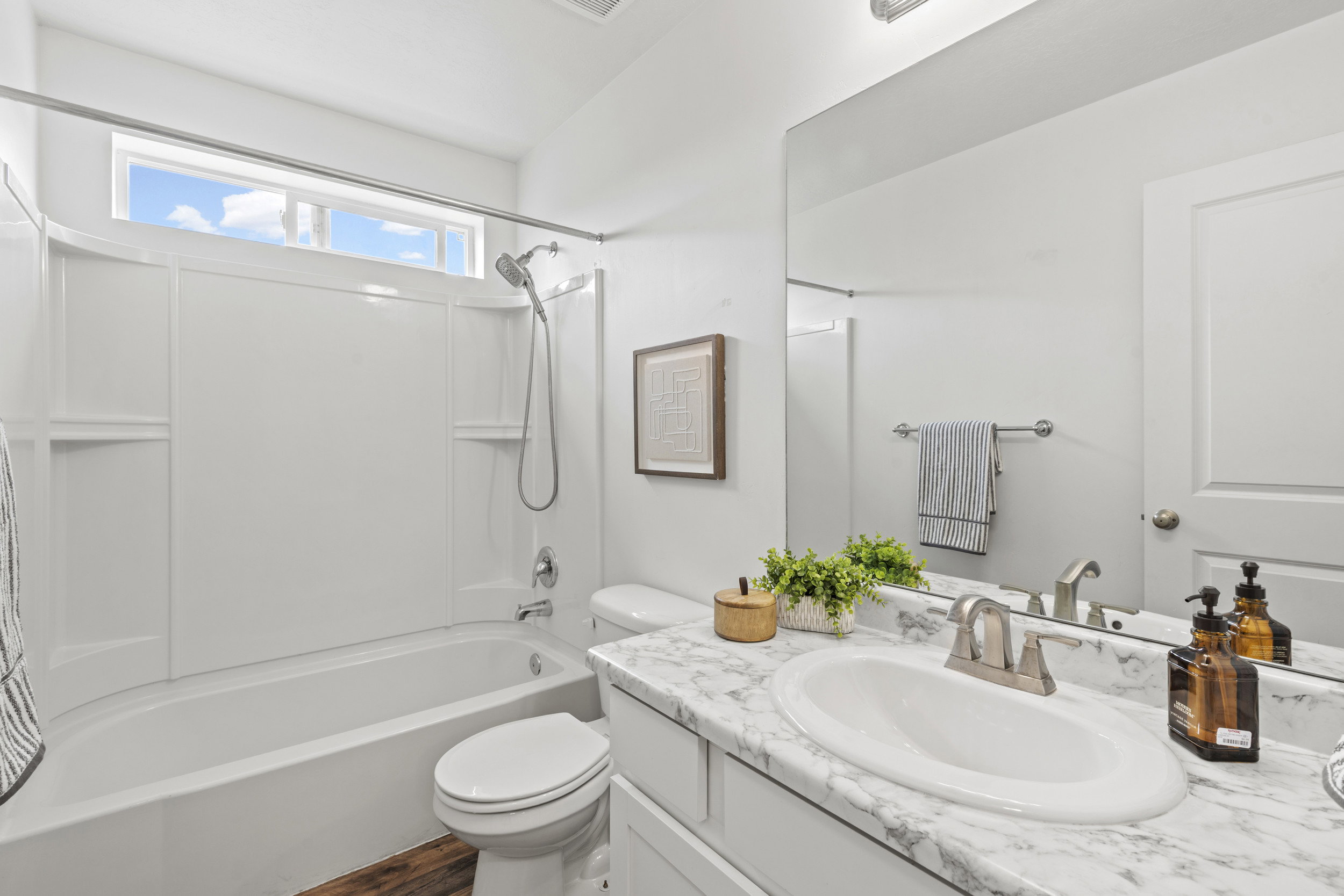 Bathroom featuring a full-size bathtub with integrated shower, single-handle faucet, and built-in shelving