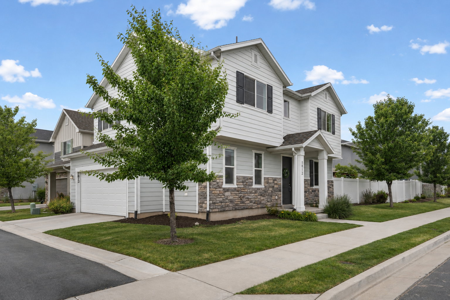 Modern two-story residence featuring light siding, stone accents, and a covered entryway