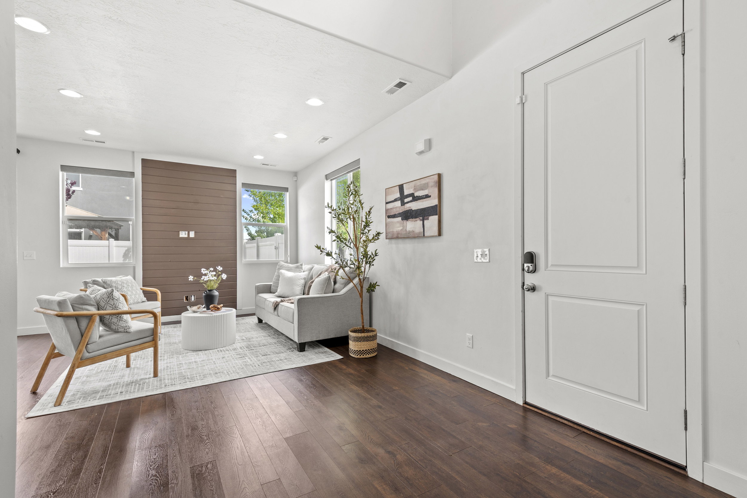 Bright living space featuring dark wood-finish flooring, recessed lighting, and a modern accent wall with horizontal paneling