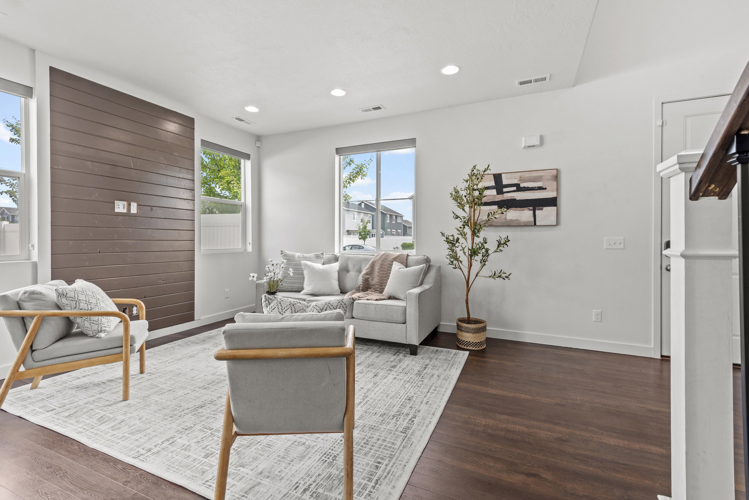 Living area featuring dark wood-finish flooring, a prominent accent wall with horizontal wood paneling, and multiple large windows