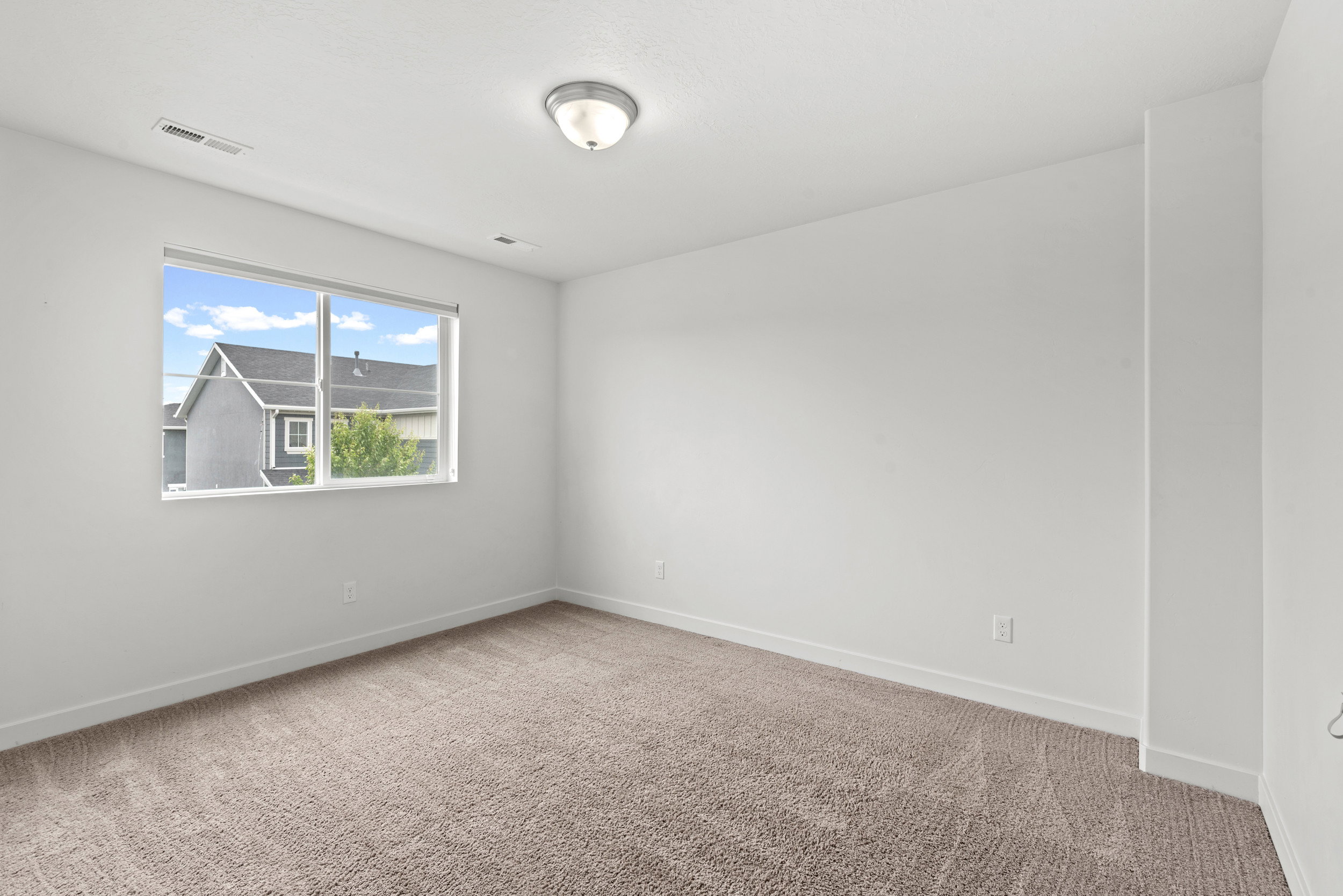 Bright interior space featuring a large window, neutral wall tones, and carpet flooring