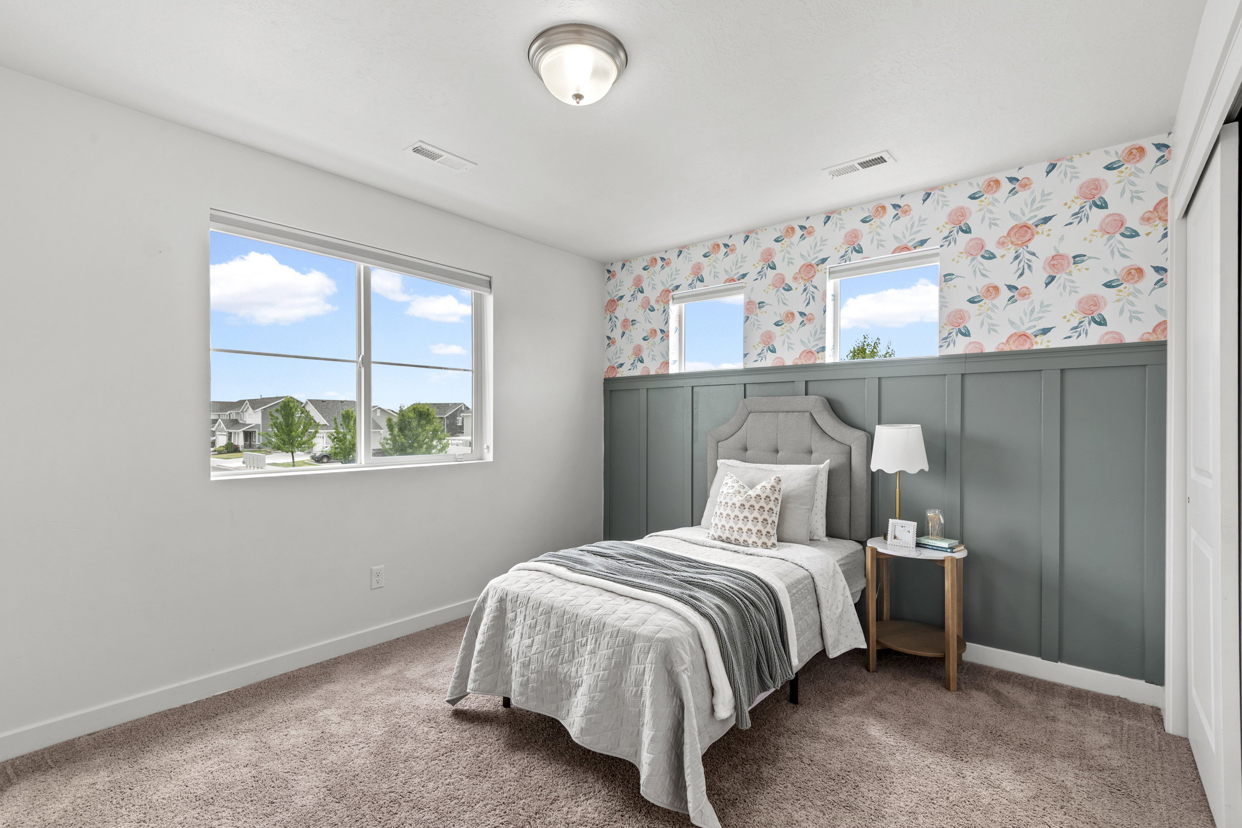 Carpeted room featuring a large window, three smaller transom windows, and a built-in board and batten wall treatment