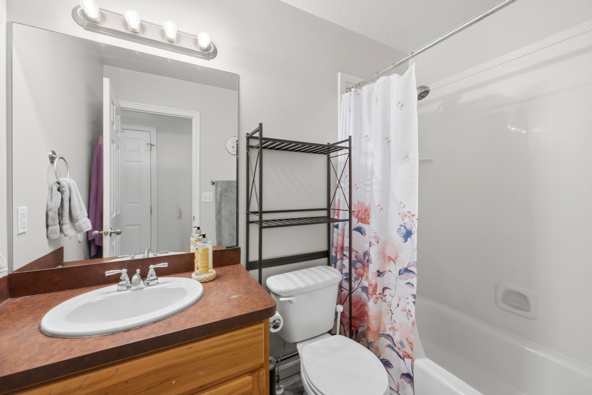 Bathroom featuring a vanity with a white oval sink, chrome-finish faucet, and coordinating mirror with overhead lighting