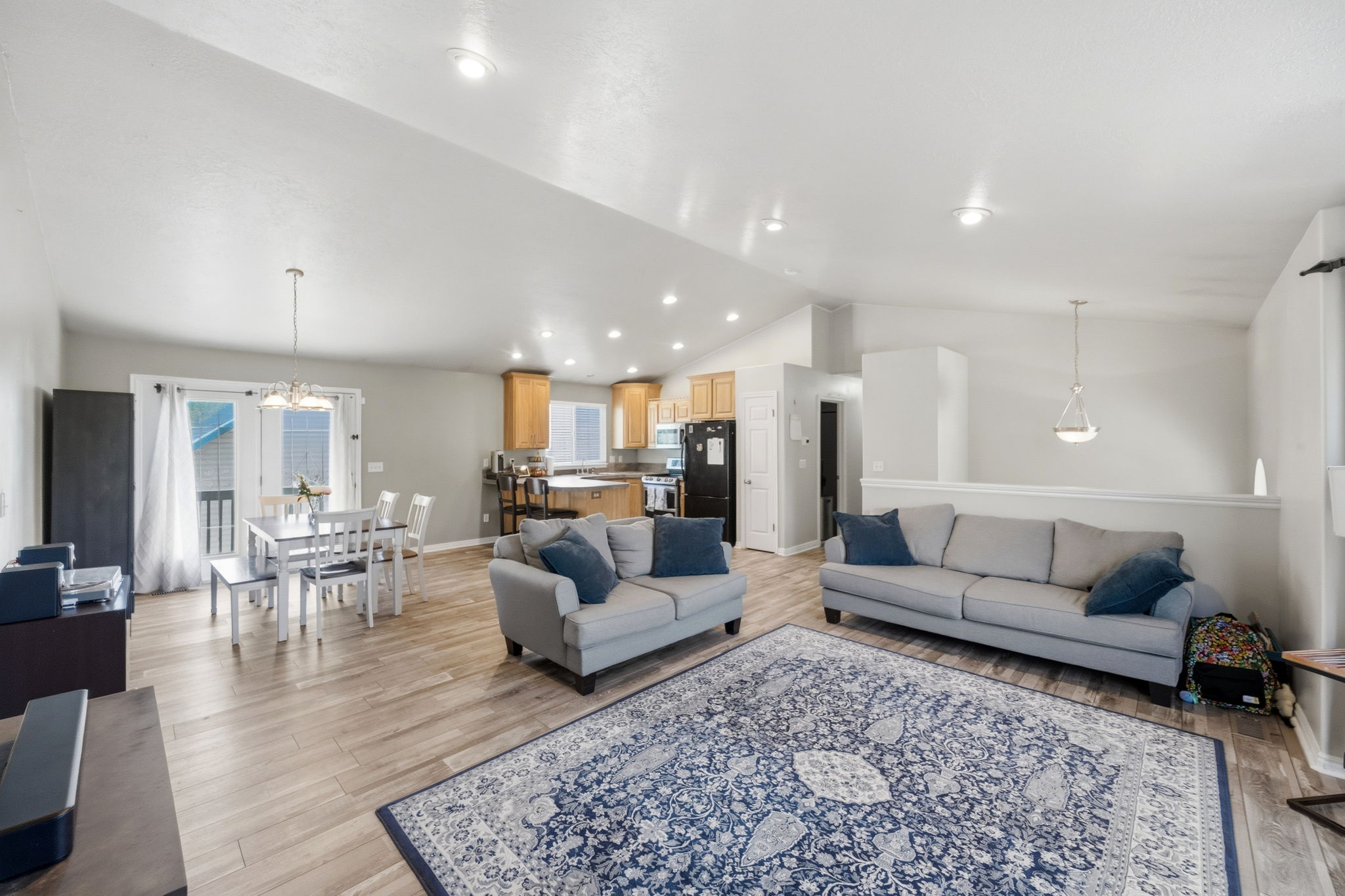 Spacious living area featuring wood-finish flooring, recessed lighting, and a vaulted ceiling
