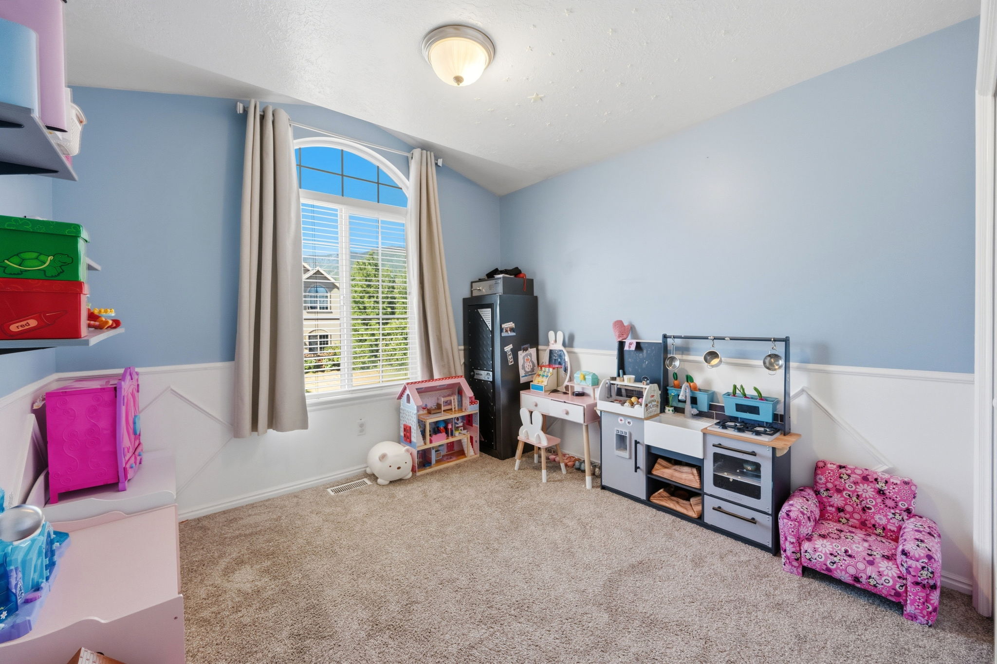 Room featuring an arched window with blinds and drapes, wall trim, wall-mounted shelving, and carpet flooring