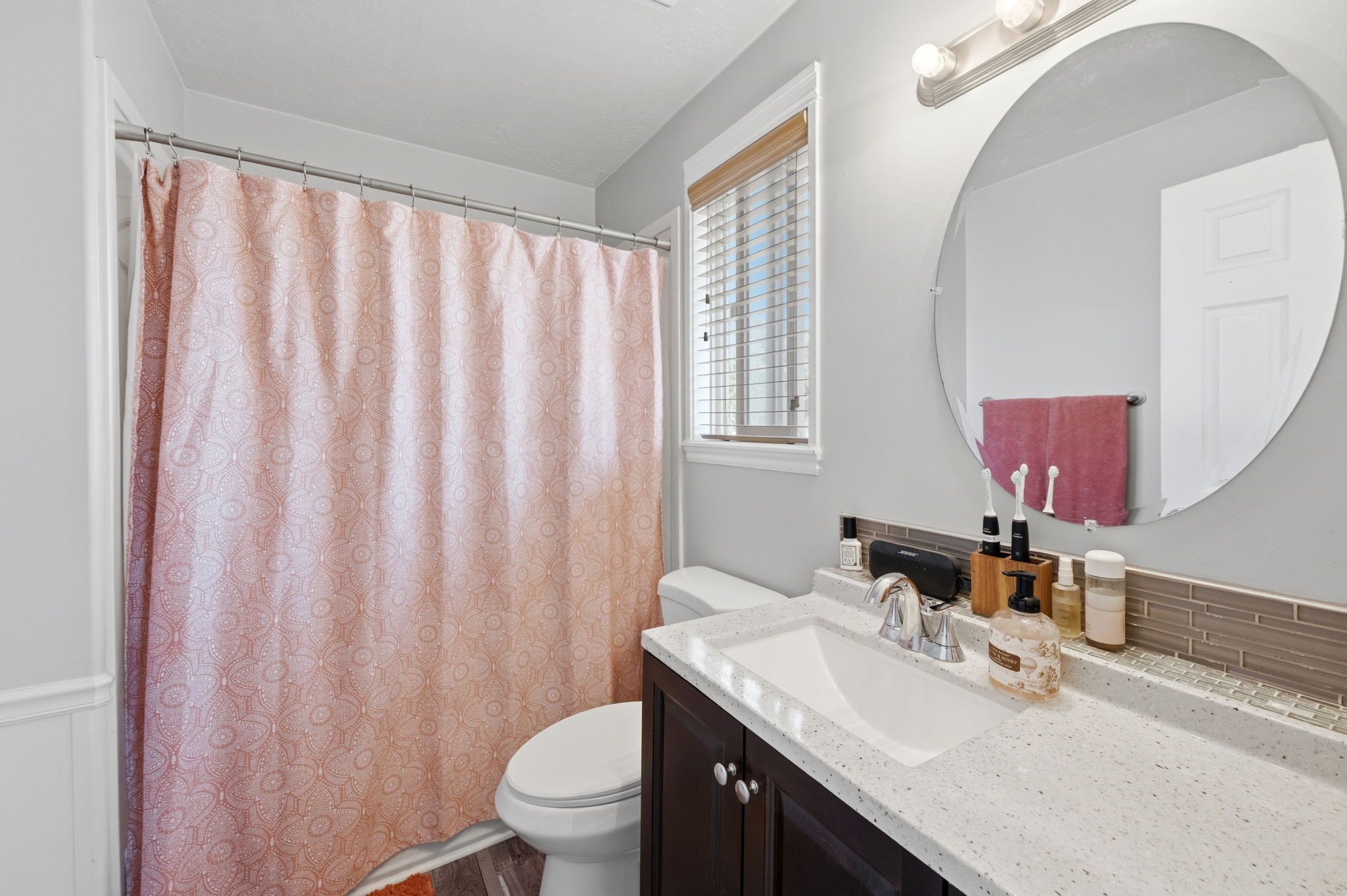 Bathroom featuring a dark wood-finish vanity with a white composite countertop, an undermount sink, and a chrome faucet