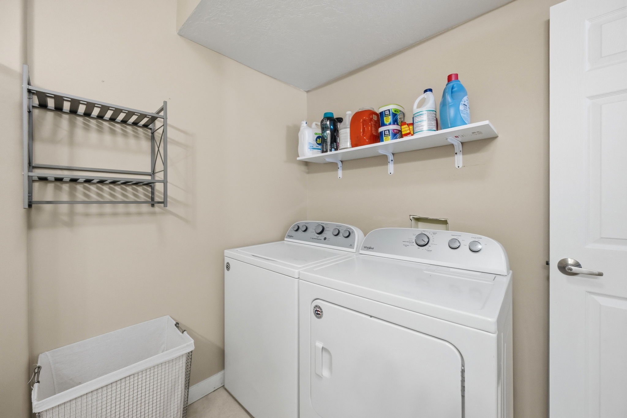 Dedicated laundry space featuring a white top-load washer, a white front-load dryer, and an upper wall-mounted shelf