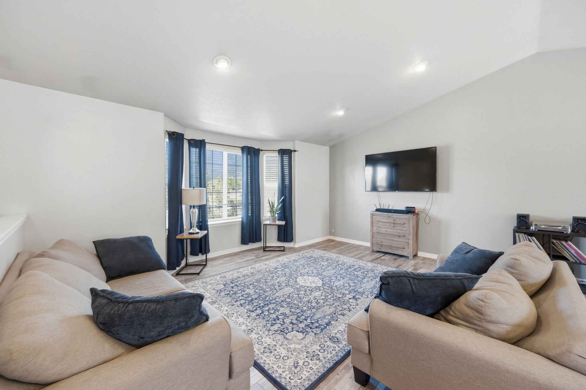Spacious living area featuring high vaulted ceilings, light-tone walls, and recessed lighting