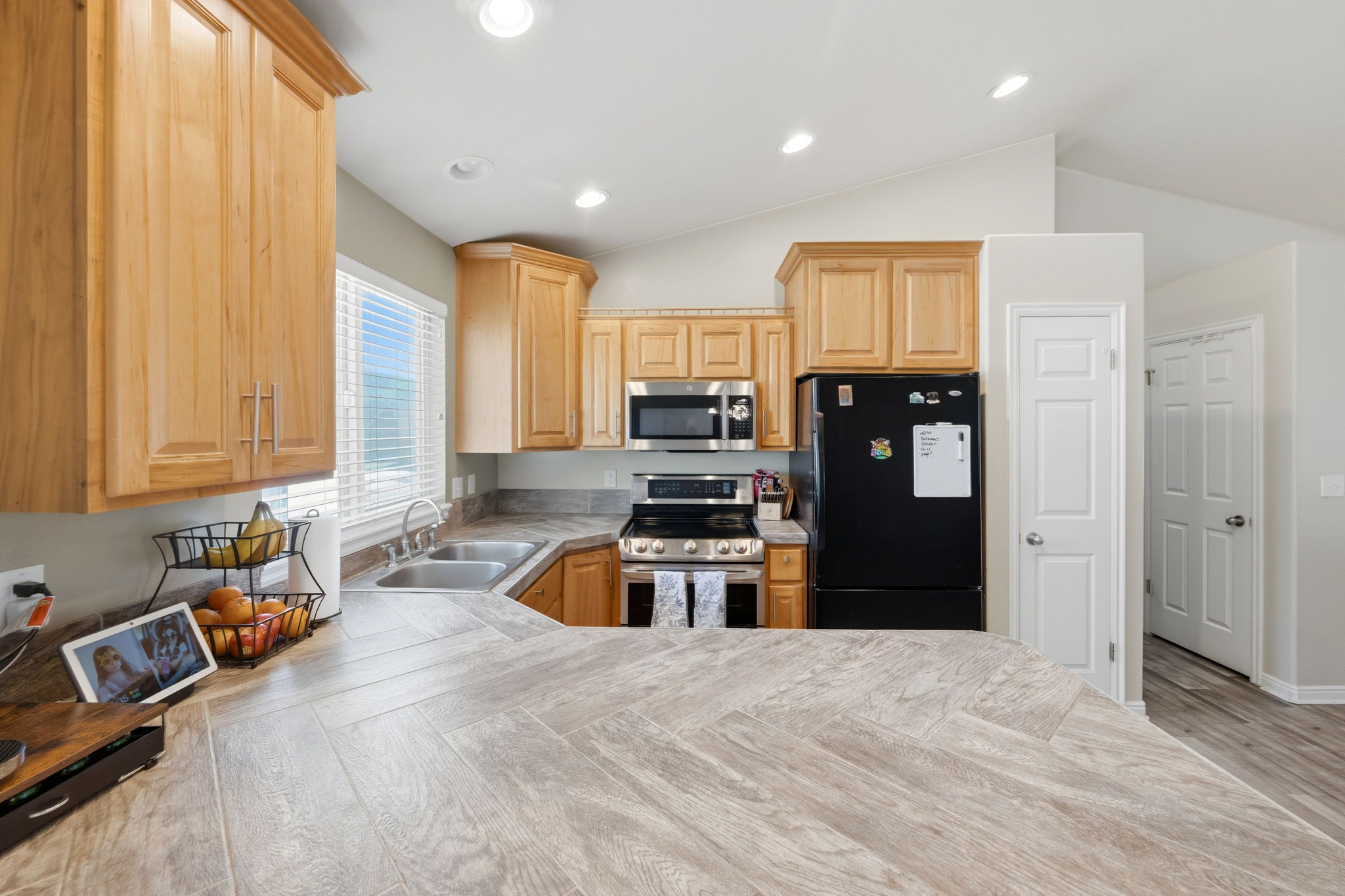 Kitchen featuring light wood cabinetry, stainless steel appliances, a double basin sink, and wood-finish countertops