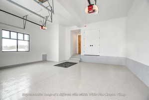 Spacious garage featuring a durable epoxy floor finish, large multi-pane window, and dual access doors