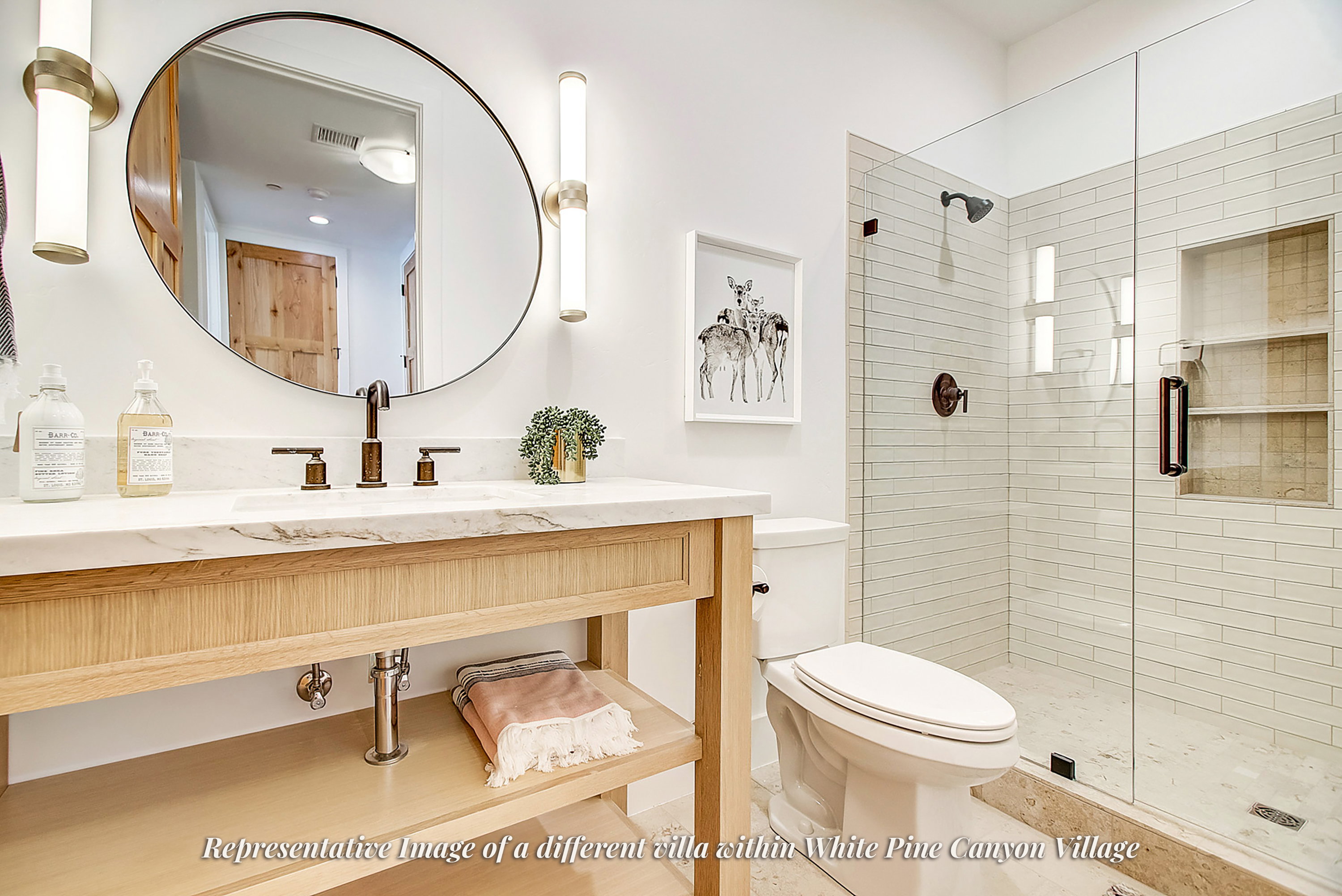 Bathroom featuring a wood-finish vanity with a stone countertop, a circular mirror, and a glass-enclosed shower with subway tile