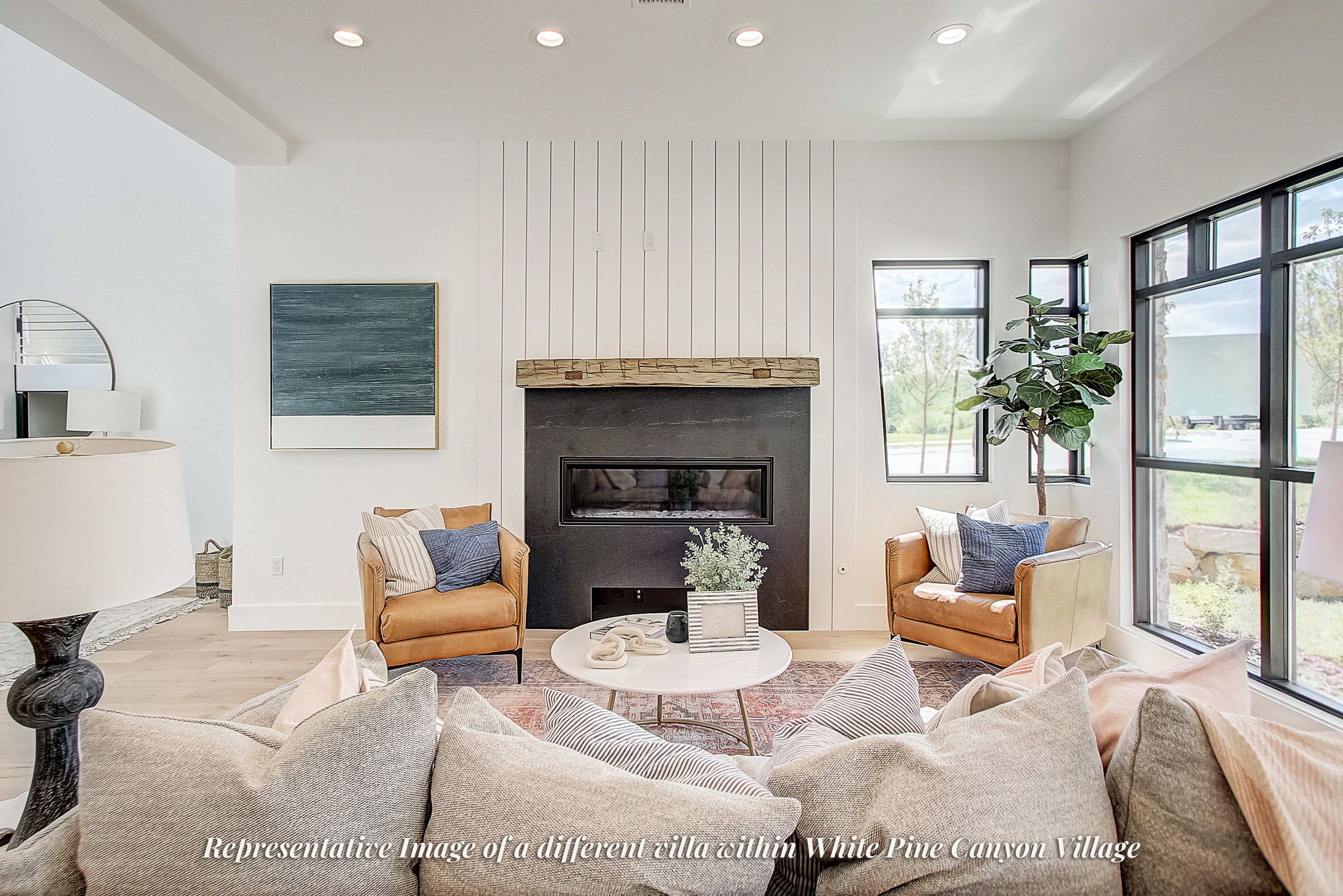 Living area featuring high ceilings with recessed lighting, light wood-finish flooring, and a fireplace with a dark stone surround and a rustic wood mantel