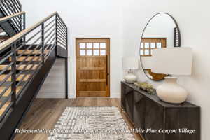 Foyer featuring a natural wood-finish entry door with multiple glass panes, a modern open-riser staircase with black metal railings and wood-finish treads, and wood-finish flooring throughout
