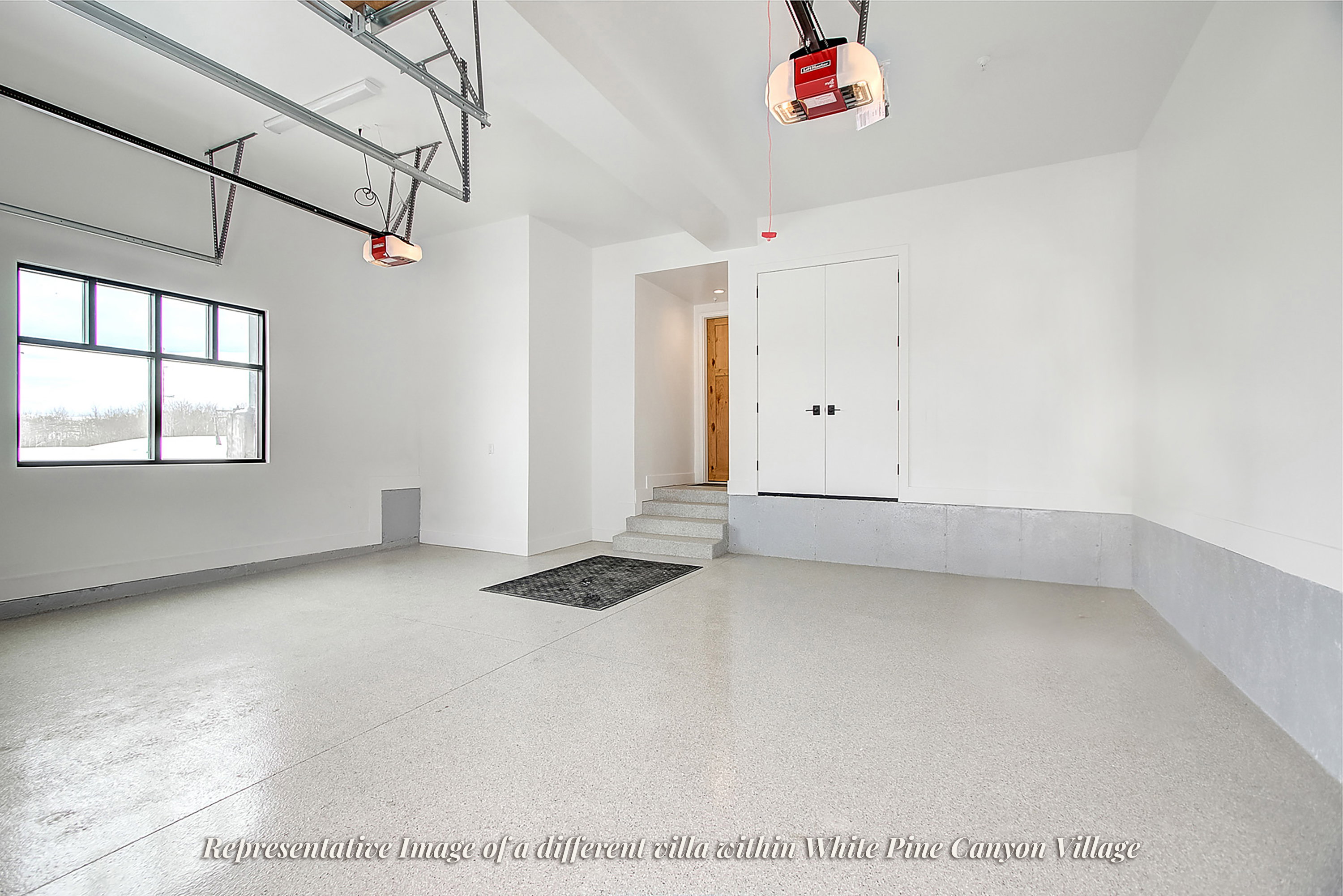 Spacious garage featuring a durable epoxy floor finish, large multi-pane window, and dual access doors
