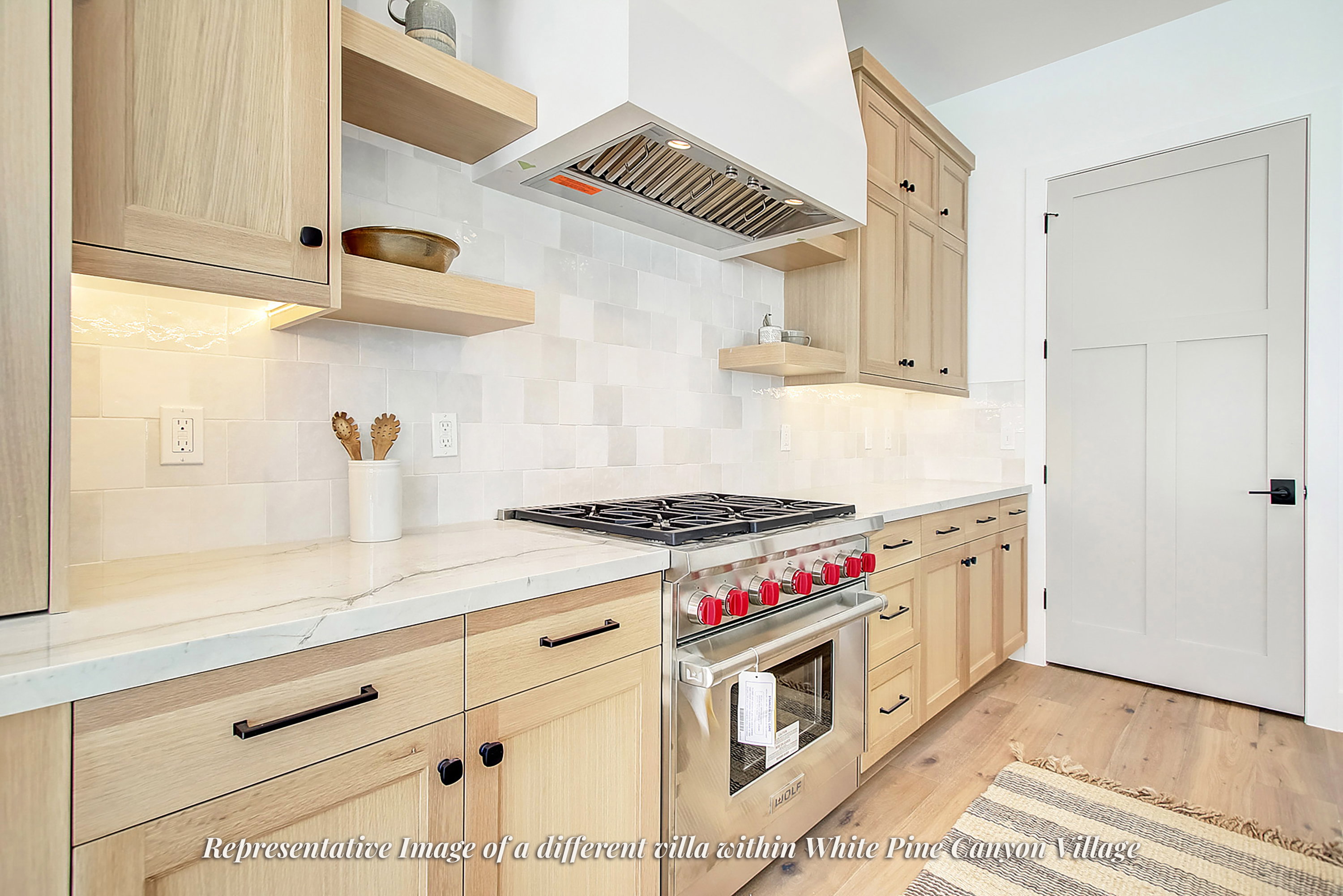 Contemporary kitchen featuring light wood cabinetry, quartz countertops, a large stainless steel range with red accents, a tile backsplash, and wood-finish flooring